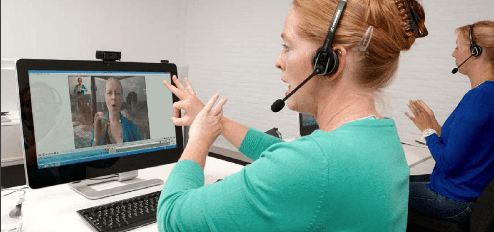 Gebarentolken van KPN Teletolk helpen een beller met een telefoongesprek.