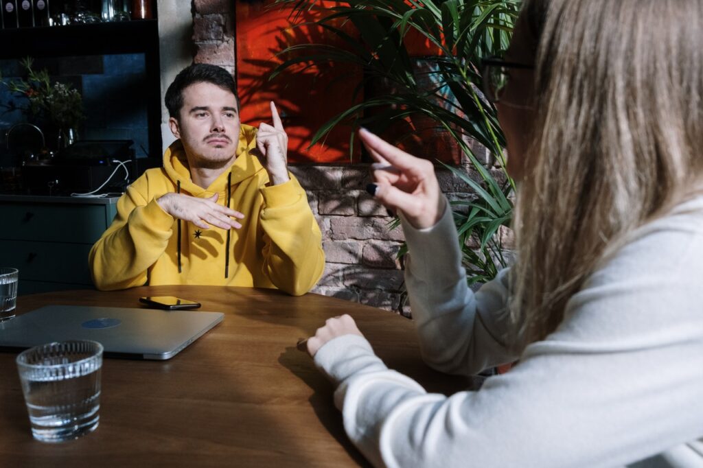 man en vrouw in cafe communiceren met elkaar in gebarentaal
