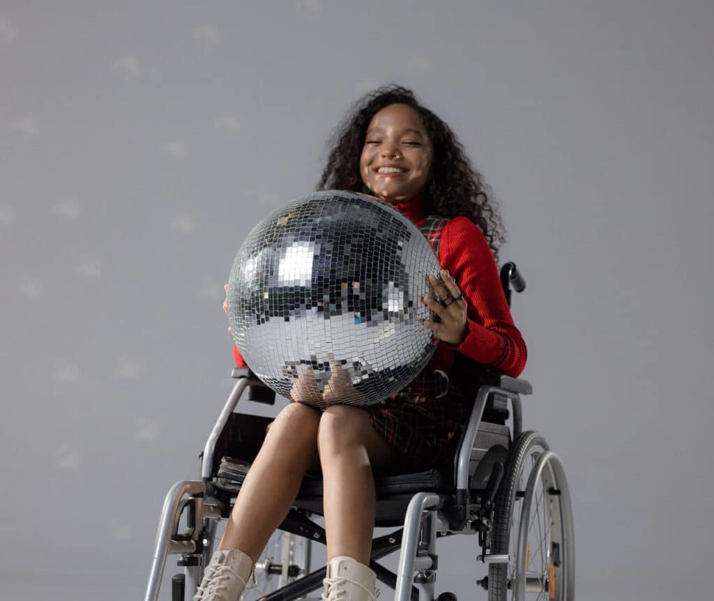 Lachend meisje in rolstoel met discobal