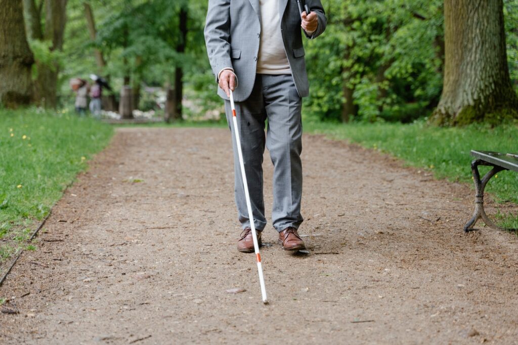 blinde man loopt met stok door park
