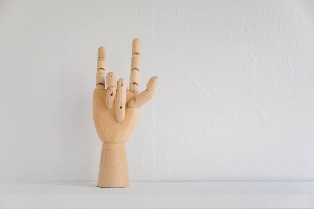 een houten hand die in gebarentaal iets duidelijk maakt