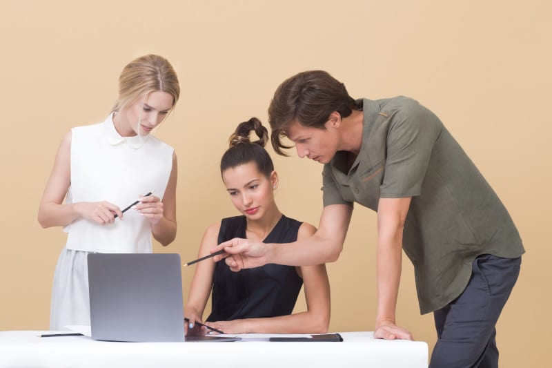 Een marketingteam kijkt gezamenlijk naar een laptop