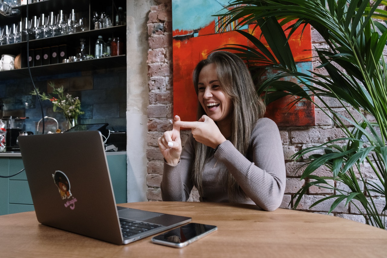 vrouw zit aan tafel met laptop en communiceert in gebarentaal