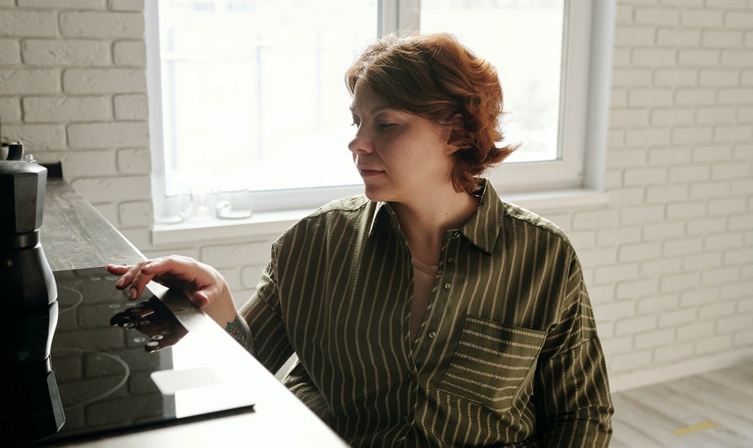 Een vrouw met kort rood haar bedient het touchscreen van haar keramische kookplaat