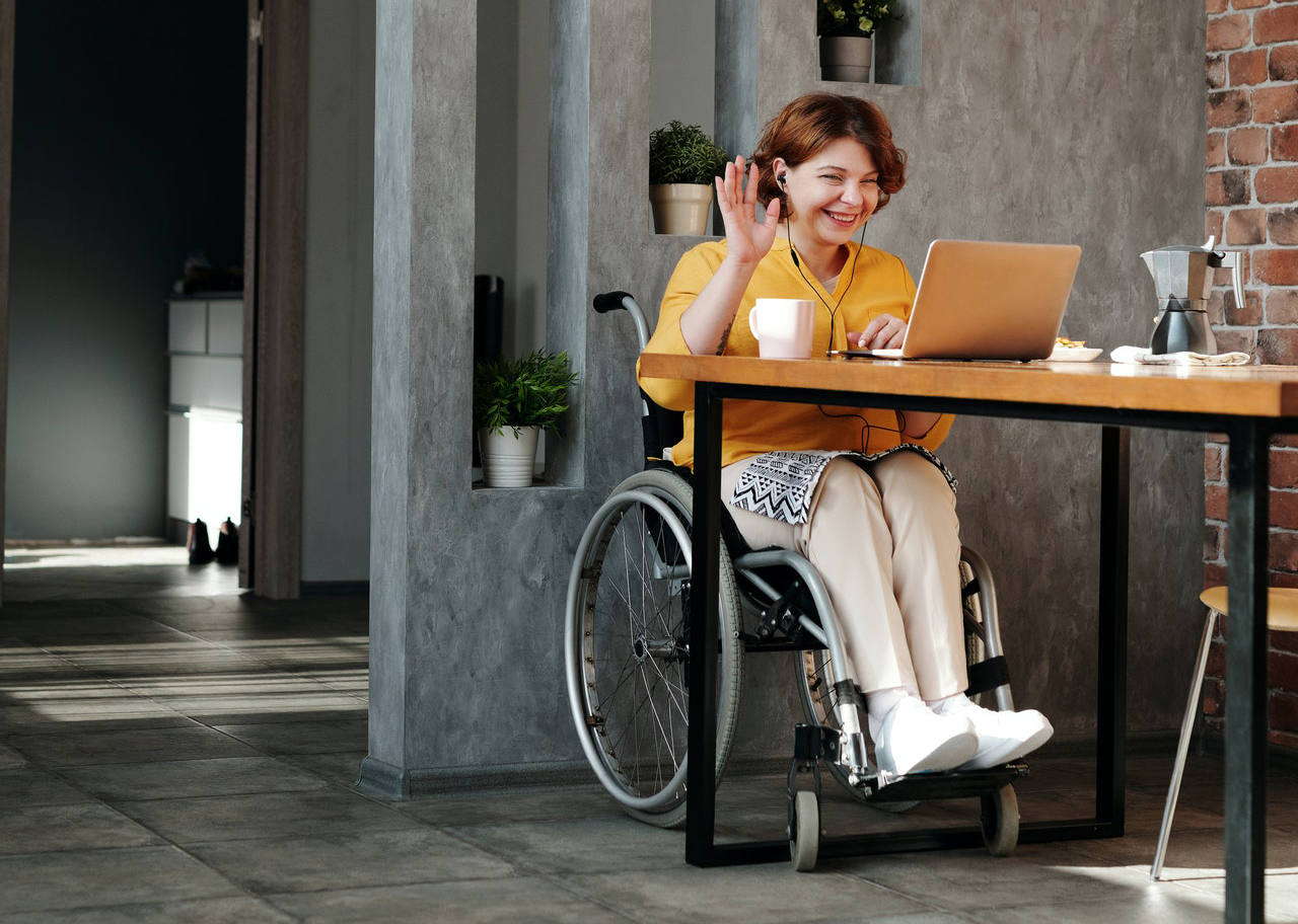 vrouw in rolstoel zit achter laptop en is aan het videobellen