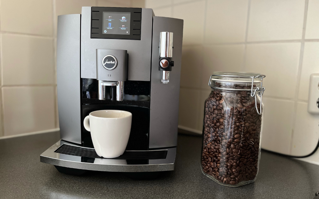 Het koffie-apparaat Jura E8waarvoor Charissa heeft gekozen, op het aanrecht, met een pot koffiebonen ernaast.