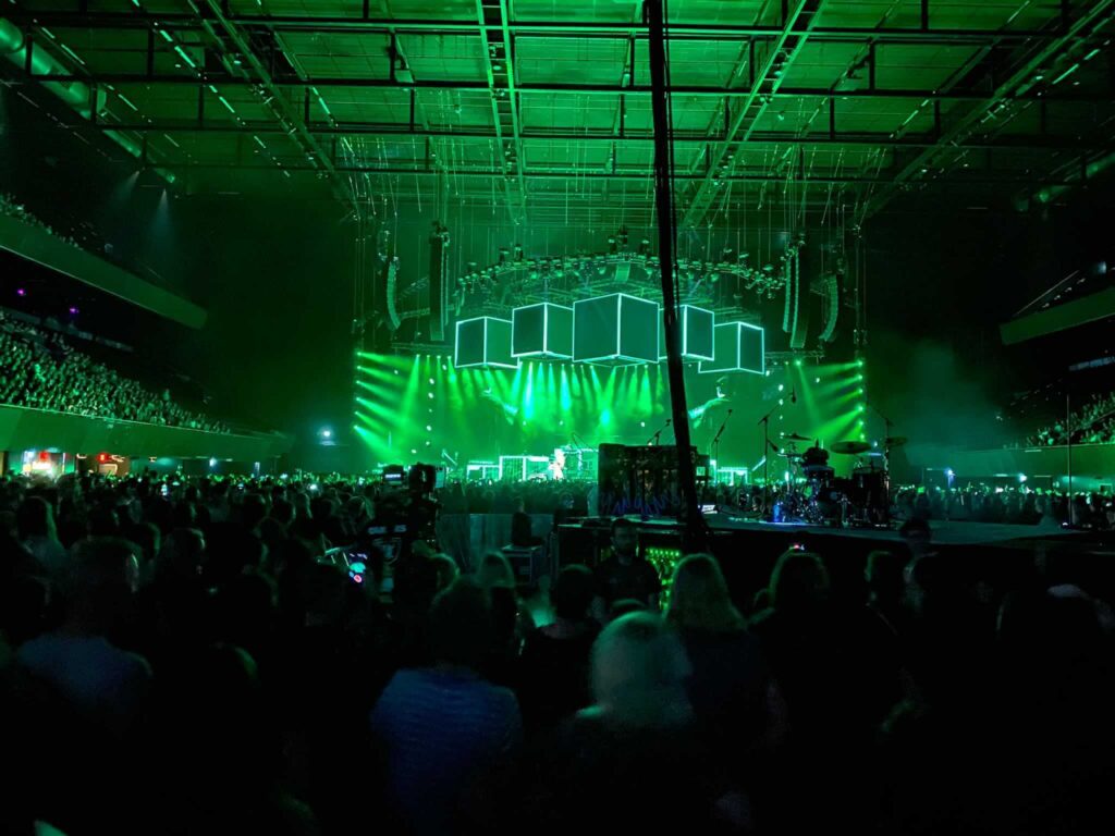 we kijken naar het podium dat groen verlicht is door lasers tijdens het concert