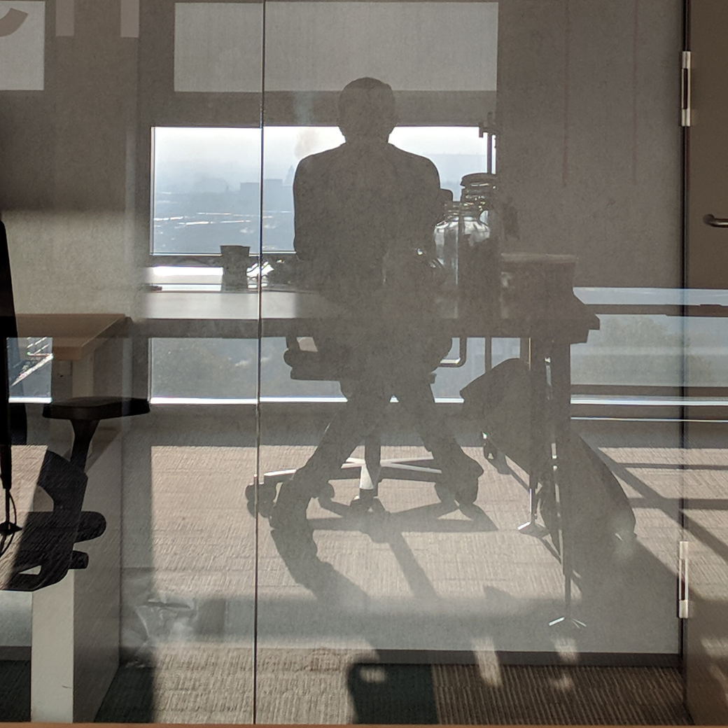 Het silhouet van Erwin, zelf gefotografeerd via zijn reflectie in een glazen wand op kantoor