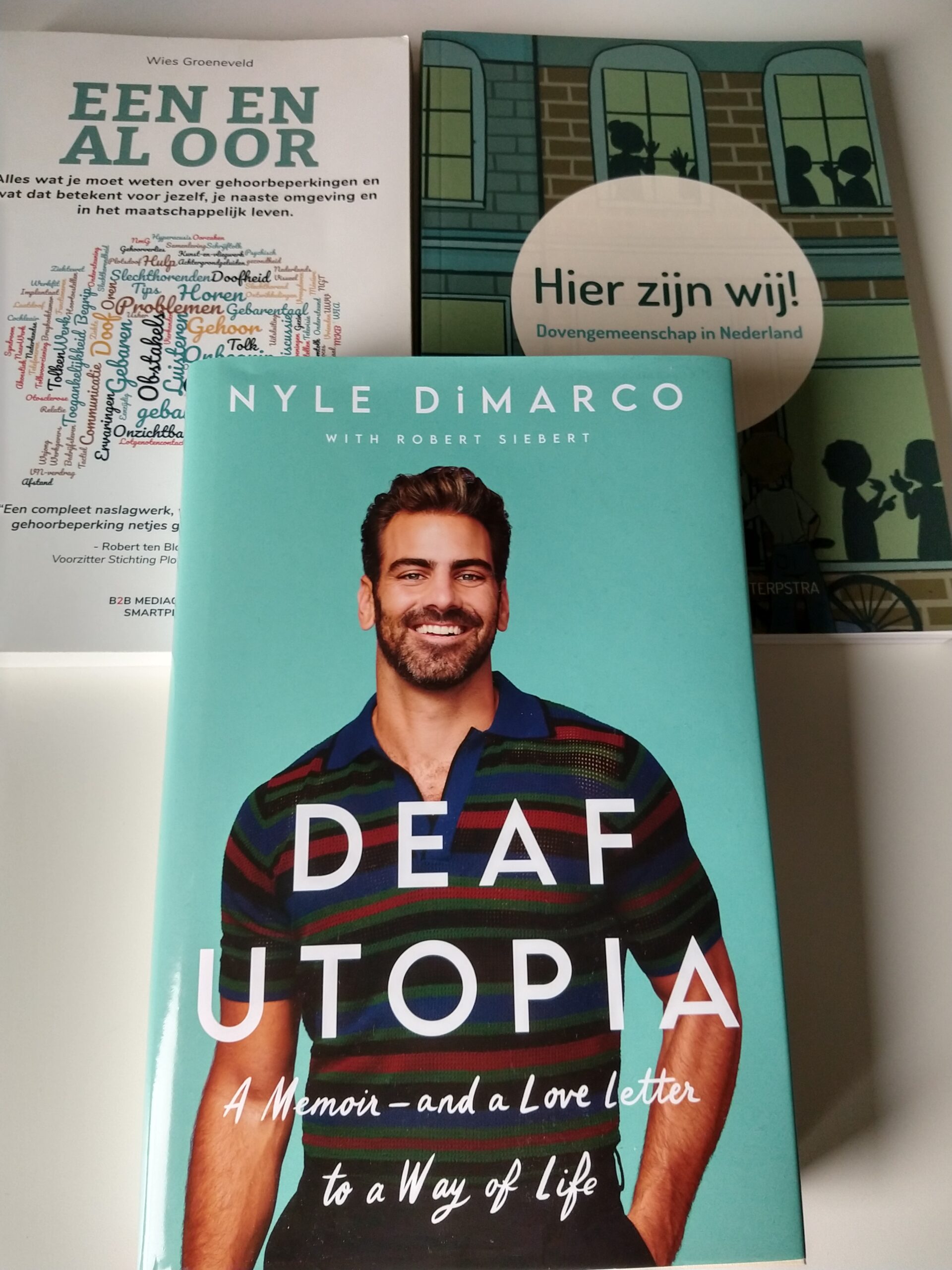 De covers van drie boeken, namelijk: 'Deaf Utopia', 'Een en al oor' en 'Hier zijn wij'